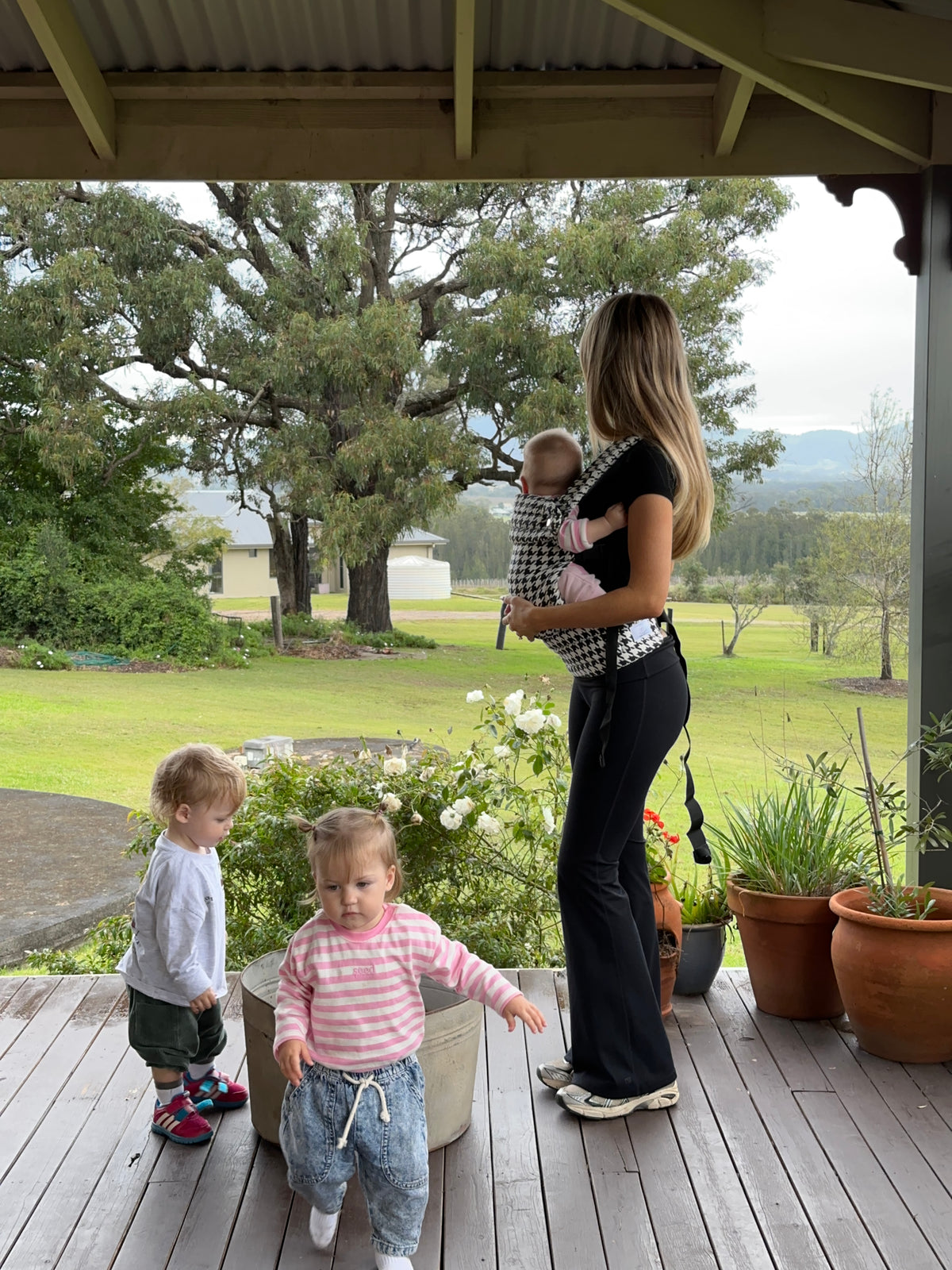 Salt & Pepper | Mum carrying baby in Haven Baby Carrier outside with toddlers and flowers